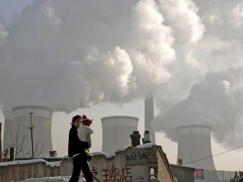 A woman and her baby walking past a coal-fired power plant on the outskirts of Datong in Shanxi province. New coal plants being built would make it virtually impossible to meet the goals set in the Paris climate accord, which aims to keep the rise in global temperatures from pre-industrial levels below 2°C. Photo: Reuters