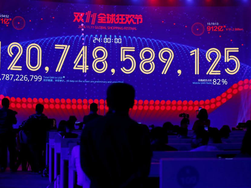 People watch a screen displaying the total value of goods sold during Alibaba Group's 11.11 Singles' Day global shopping festival last year.