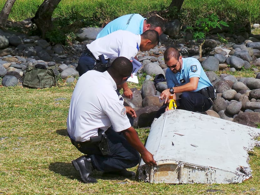 French gendarmes and local police inspecting a large piece of plane debris which was found on the beach in Saint-Andre, on the French Indian Ocean island of Reunion. Aviation experts said it may be a moving wing surface known as a flaperon. Photo: Reuters