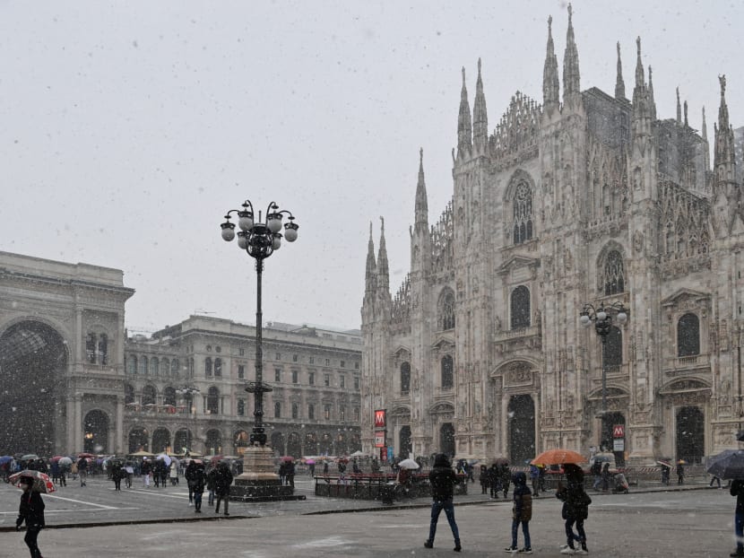 People walking across Piazza del Duomo past the cathedral as snow falls in Milan on Dec 8, 2021.
People walking across Piazza del Duomo past the cathedral as snow falls in Milan on Dec 8, 2021.