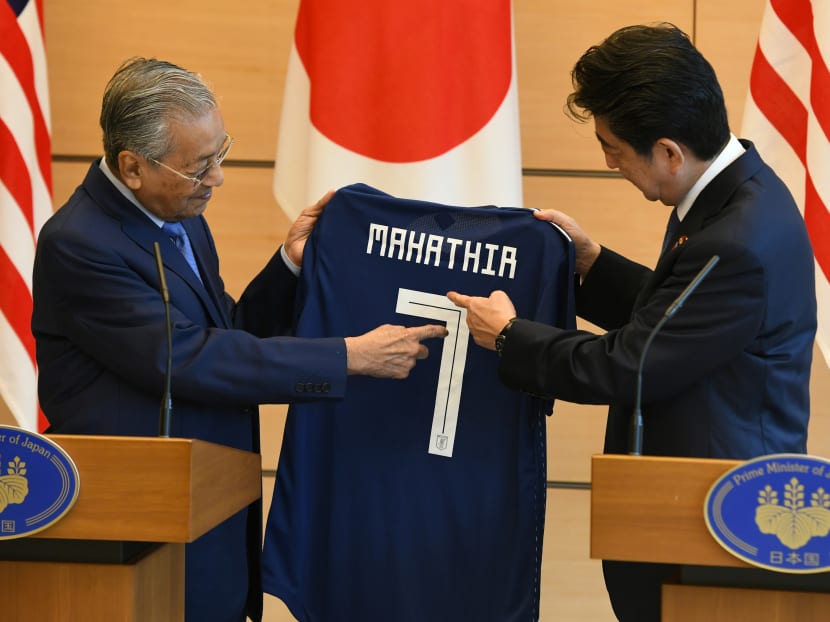 Malaysian Prime Minister Tun Dr Mahathir Mohamad receives a Japanese national football jersey as a present from his Japanese counterpart Shinzo Abe during their joint press remarks in Tokyo. Dr Mahathir says Malaysia has asked the Japanese government for yen credit to help solve its S$336 billion debt.