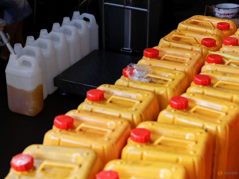 FILE PHOTO: A worker fills jerrycans with cooking oil at a distribution station in Jakarta, Indonesia, May 20, 2022. REUTERS/Willy Kurniawan