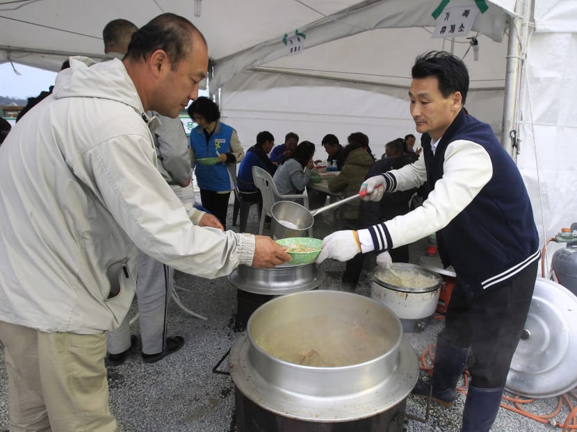 Lim Jang-young, 58, volunteer and Japanese restaurant owner,, ladles out a bowl of traditional beef soup to a relative of a passenger aboard the sunken ferry Sewol in Jindo, South Korea.  Photo: AP