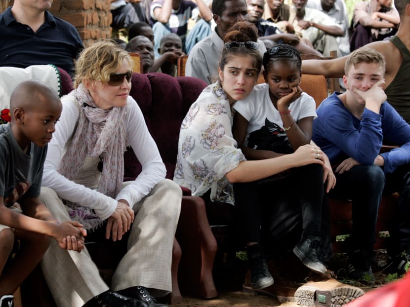 This file photo taken on April 2, 2013 shows US Pop Star Madonna (2nd left) sitting with her biological and adopted children (left to right) David Banda, Lourdes, Mercy James, and Rocco at Mkoko Primary School, one of the schools Madonna's Raising Malawi organization has built jointly with US organization BuildOn, during a visit in the region of Kasungu, central Malawi. Photo: AFP