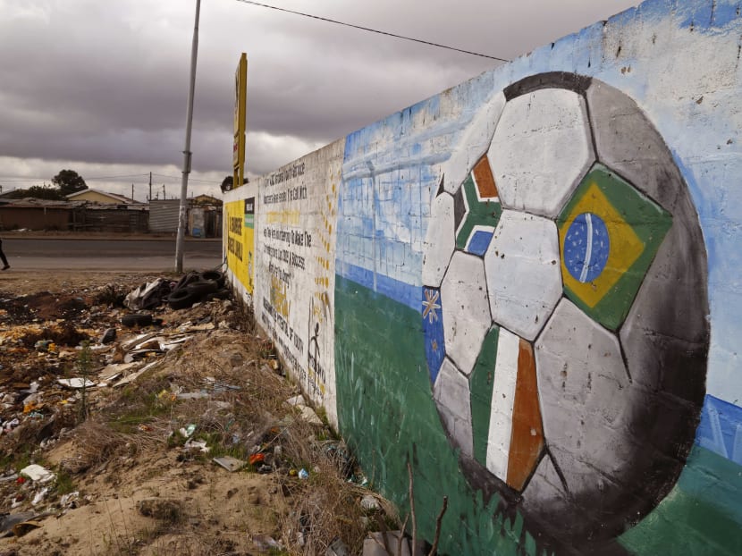 A soccer ball with different colored flags, including the South African national flag, right, painted on a wall in the township of Khayelitsha, South Africa, on May 28, 2015. Photo: AP