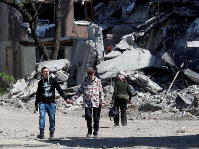 Local residents walk past a destroyed building during Ukraine-Russia conflict in the southern port city of Mariupol, Ukraine May 12, 2022. Local residents walk past a destroyed building during Ukraine-Russia conflict in the southern port city of Mariupol, Ukraine May 12, 2022.