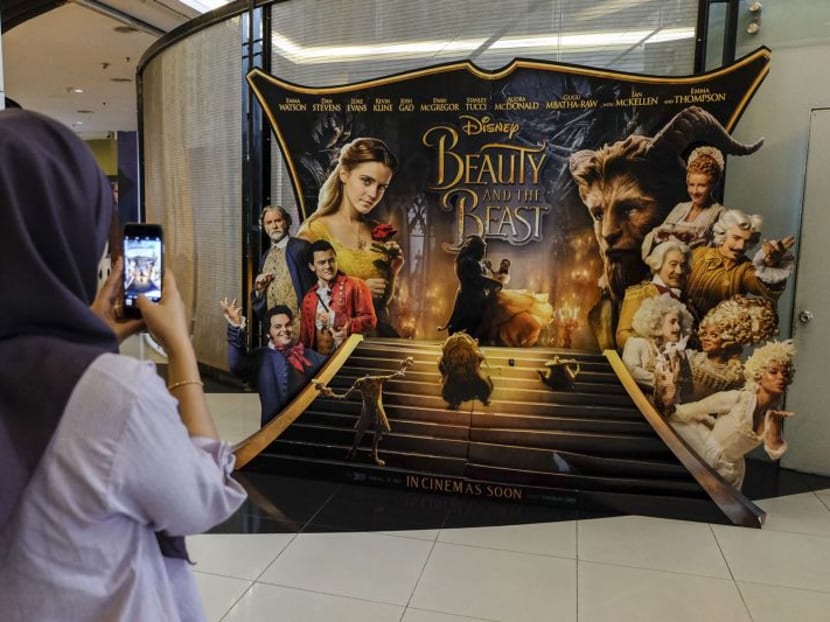 A woman takes a picture of the Beauty and the Beast poster displayed at a cinema in Kuala Lumpur on March 16, 2017. Photo: Malay Mail Online