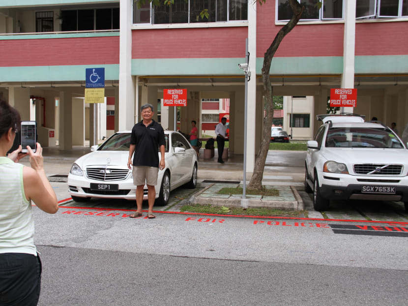 People posing with Madam Halimah Yacob's presidential car parked in a specially-marked lot at her public housing block in Yishun. Photo: Esther Leong/TODAY