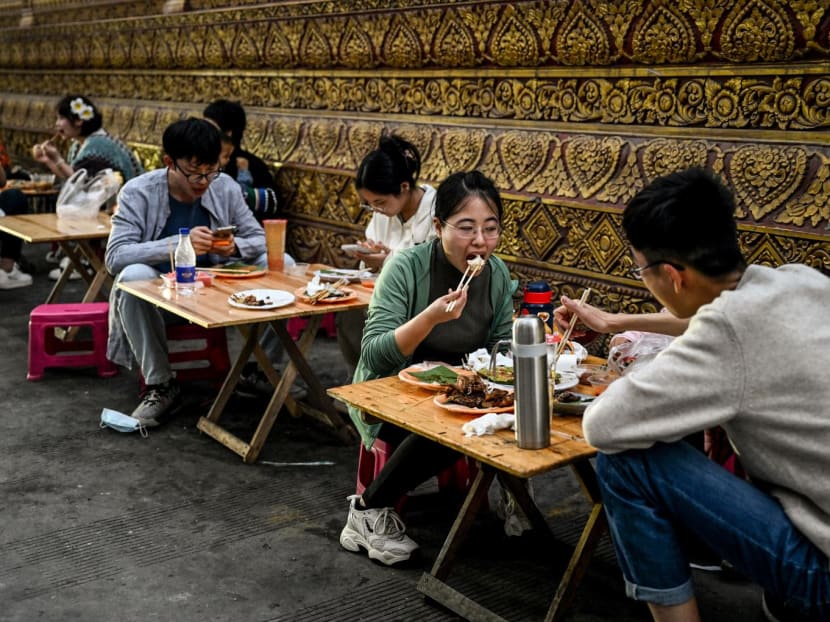 People eat along a street in Jinghong City in Xishuangbanna Dai Autonomous Prefecture in China's south Yunnan province on Jan 9, 2023.