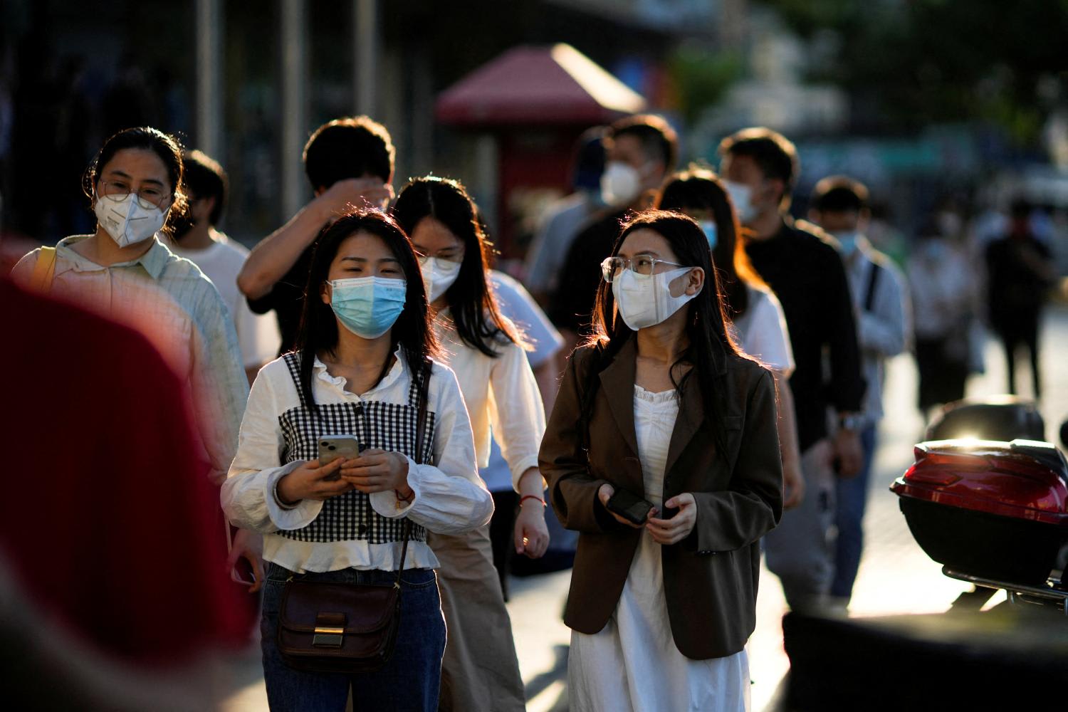 Office workers wearing protective face masks walk on a street, after the lockdown placed to curb the Covid-19 outbreak was lifted in Shanghai, China on June 7, 2022. 

