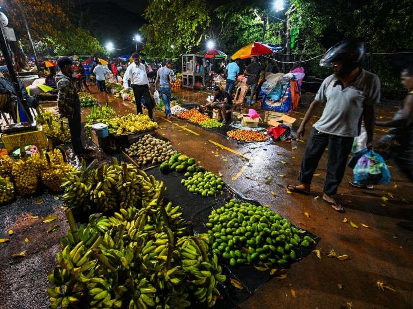 People buy vegetables at a night market in Colombo on Nov 8, 2022.
