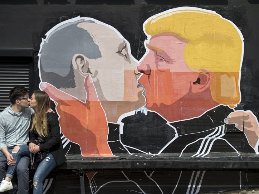 A couple kisses in front of graffiti depicting Russian President Vladimir Putin, left, and Republican presidential candidate Donald Trump, on the walls of a bar in the old town in Vilnius, Lithuania,  Saturday, May 14, 2016. Photo: AP