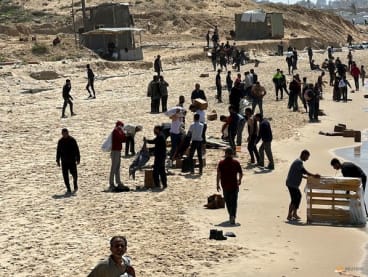 Palestinians gather on a beach as they collect aid airdropped by an airplane, amid the ongoing conflict between Israel and Hamas, in the northern Gaza Strip, on March 25, 2024.