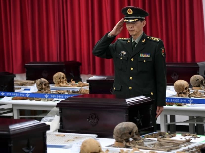 A Chinese military officer salutes near the remains of Chinese soldiers, who fought during the Korean War, during ceremonial rites to place the remains at a temporary military ossuary in Incheon, west of Seoul. Photo: AFP