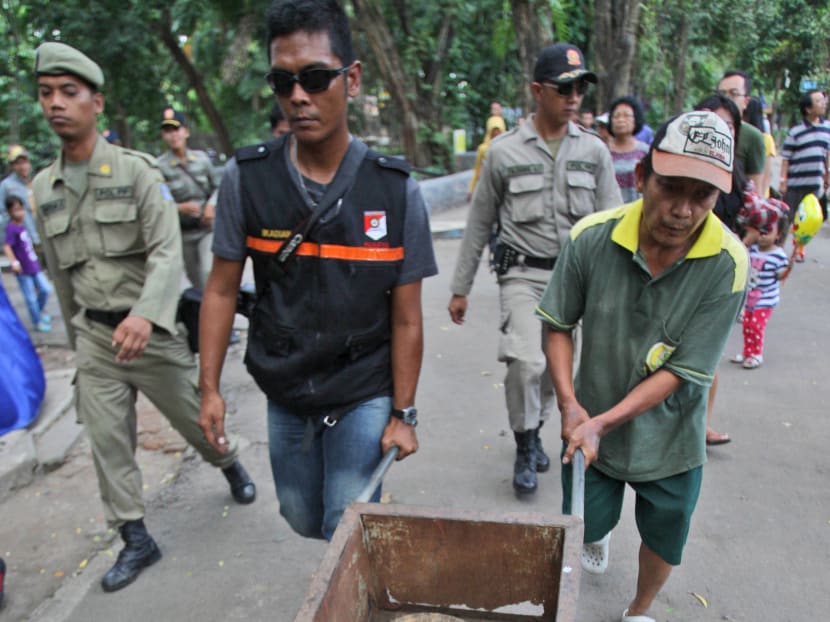 A police officer and a zoo employee take a Komodo dragon that was found dead in its cage for an autopsy, at Surabaya Zoo in Surabaya, East Java, Indonesia, Saturday, Feb. 1, 2014. Photo: AP
