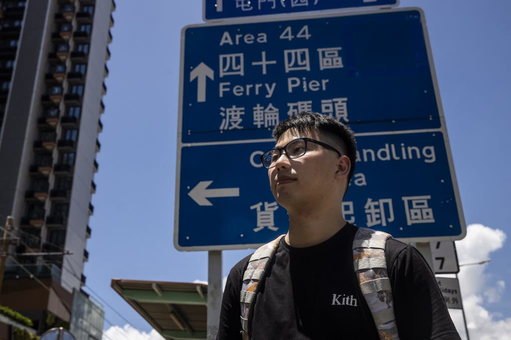 This picture taken on July 10, 2022, in Hong Kong shows Mr Gary Yau standing in front of a street sign that was manually designed and handmade by prison inmates between the 1970s and 1990s. 