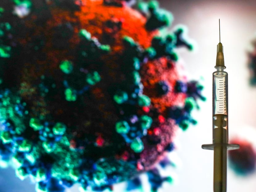 A photo illustration showing a medical syringe in front of a microscopic image of the coronavirus.