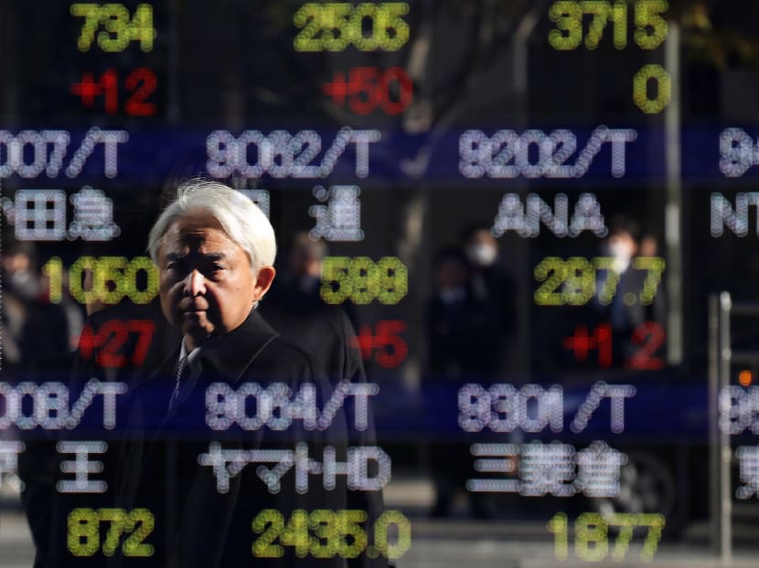 A pedestrian is reflected on an electronic stock board of a securities firm in Tokyo, Dec 19, 2014.  Photo: AP