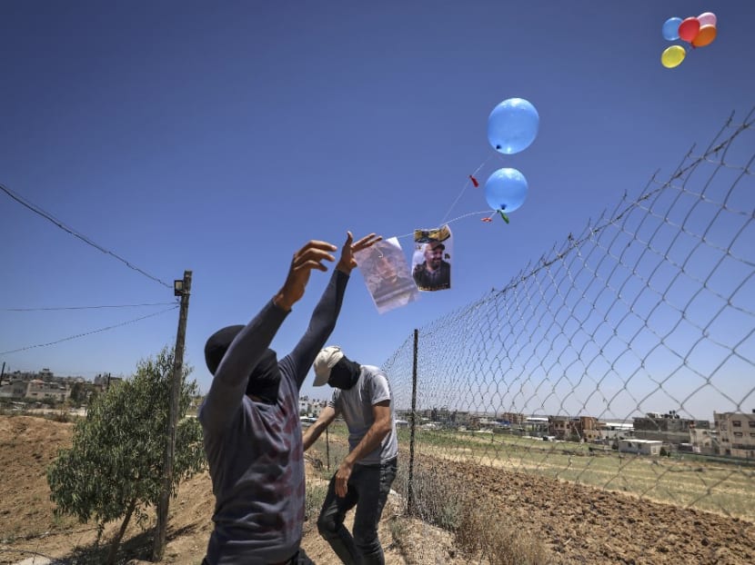 Masked Palestinian supporters of the Islamic Jihad movement prepare incendiary balloons east of Gaza city, to launch across the border fence towards Israel on June 15, 2021. Masked Palestinian supporters of the Islamic Jihad movement prepare incendiary balloons east of Gaza city, to launch across the border fence towards Israel on June 15, 2021.