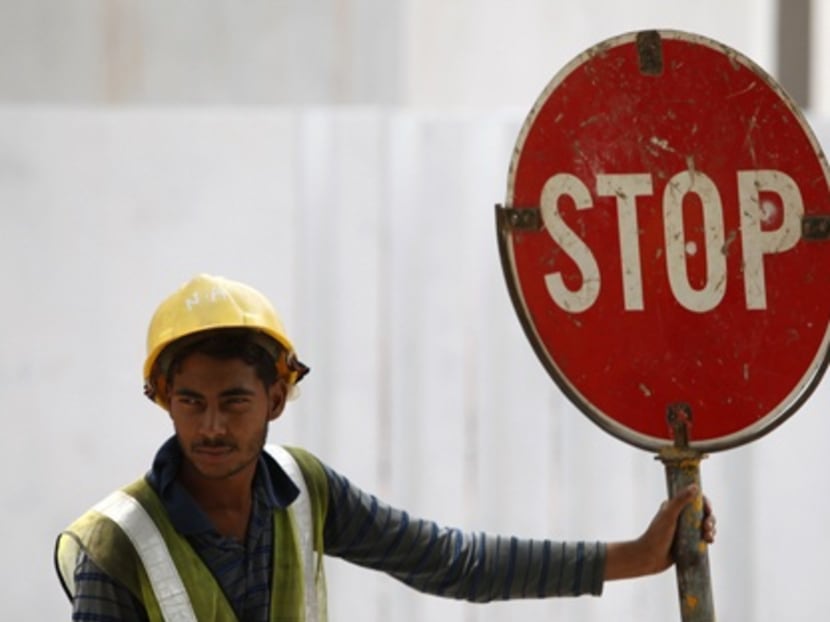 A foreign worker directs traffic along a busy construction site in Singapore on May, 2013. Photo: Reuters