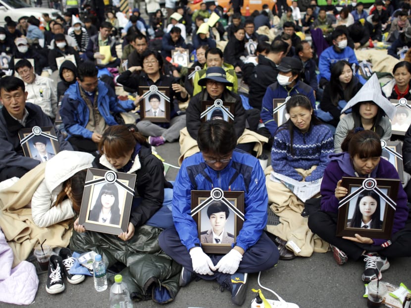 Family members holding the portraits of the victims of the sunken ferry Sewol, sit on the street near the presidential Blue House in Seoul, South Korea, Friday, May 9, 2014. Family members marched to the presidential Blue House in Seoul early Friday calling for a meeting with President Park Geun-hye but ended up sitting on streets near the presidential palace after police officers blocked them. Park’s office said a senior presidential official plans to meet them later Friday. (AP Photo/Lee Jin-man)