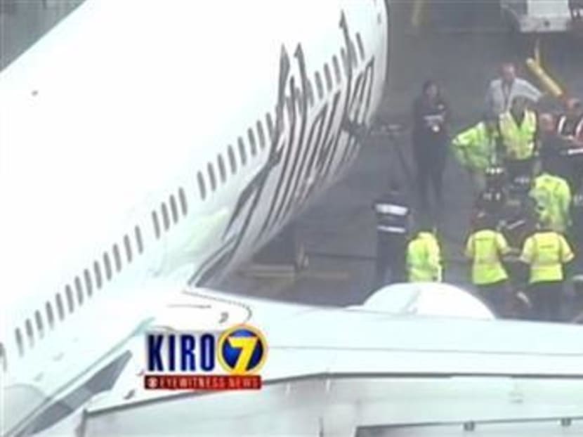 In this April 13, 2015, file photo, workers walk with the Menzies Aviation cargo worker after the worker was removed from the cargo hold of an Alaska Airlines passenger airplane at Seattle-Tacoma International Airport, in Seattle. Photo: AP