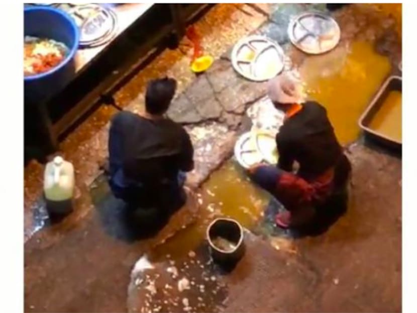 Screengrab of the restaurant’s employees using water puddled beside a drain to clean dishes.