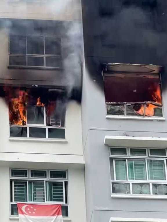 In a video posted by a Facebook user, a fire can be seen engulfing a flat as thick black smoke billows out from it, coating the exterior walls of the housing block with black soot. In a video posted by a Facebook user, a fire can be seen engulfing a flat as thick black smoke billows out from it, coating the exterior walls of the housing block with black soot.