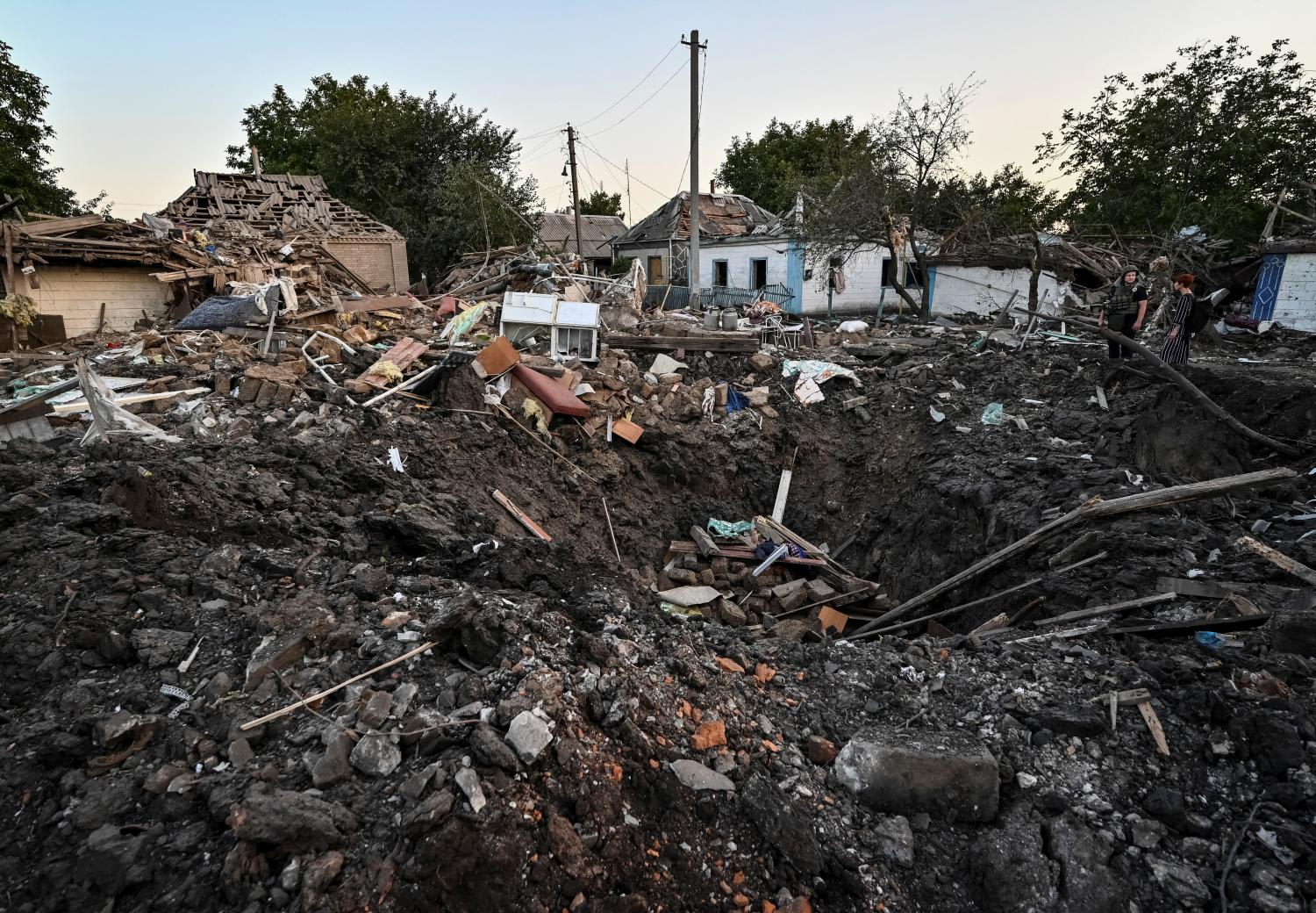 People stand next to a residential house destroyed by a Russian military strike, as Russia's attack on Ukraine continues, in Chaplyne, Dnipropetrovsk region, Ukraine Aug 24, 2022.