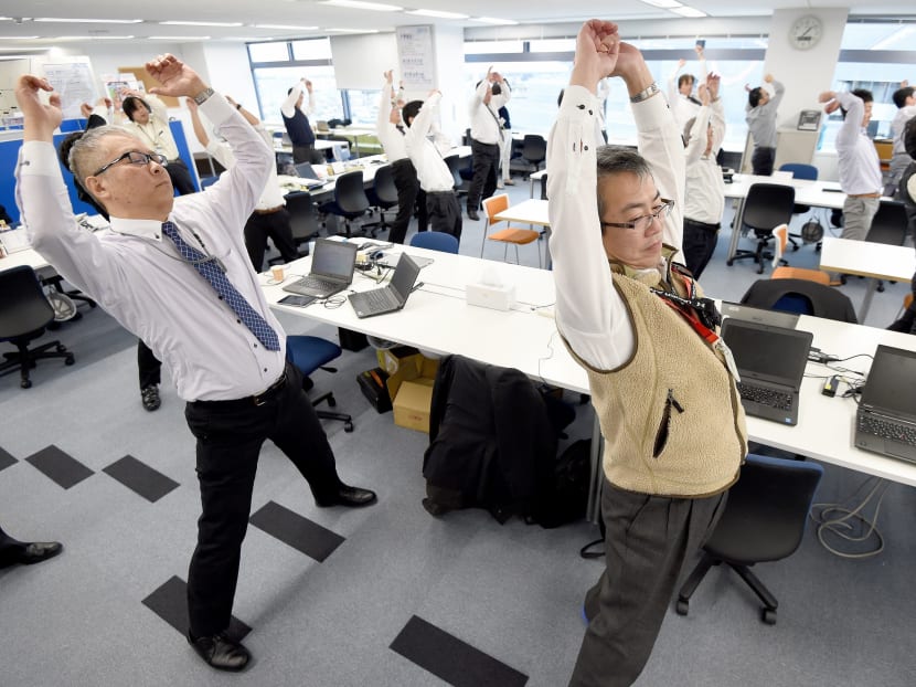 This photo taken on November 10, 2016 shows employees of an information technology company exercising together in their office after lunchtime in Tokyo.  Photo: AFP