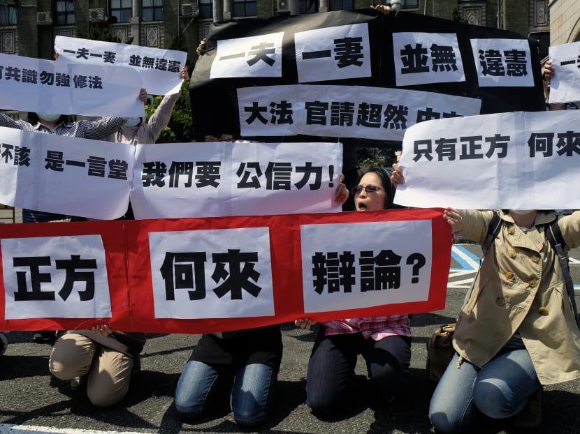 Anti-same sex rights activists display the signs reading "one husband, one wife do not go against the constitution" outside the Judicial Yuan in Taipei. Photo: AFP