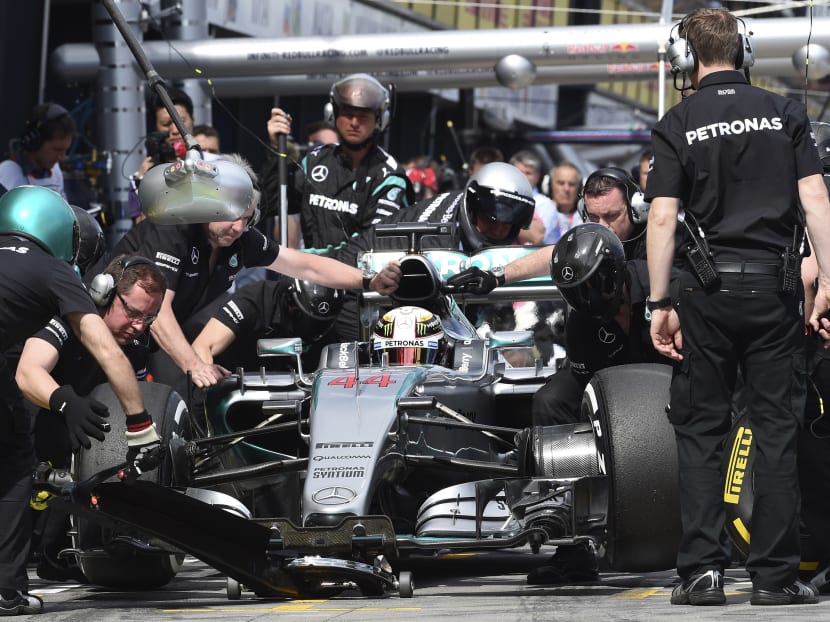 Mercedes driver Lewis Hamilton of Britain sits in his car as his pit crew do a tyre change during free practice. Photo: AP