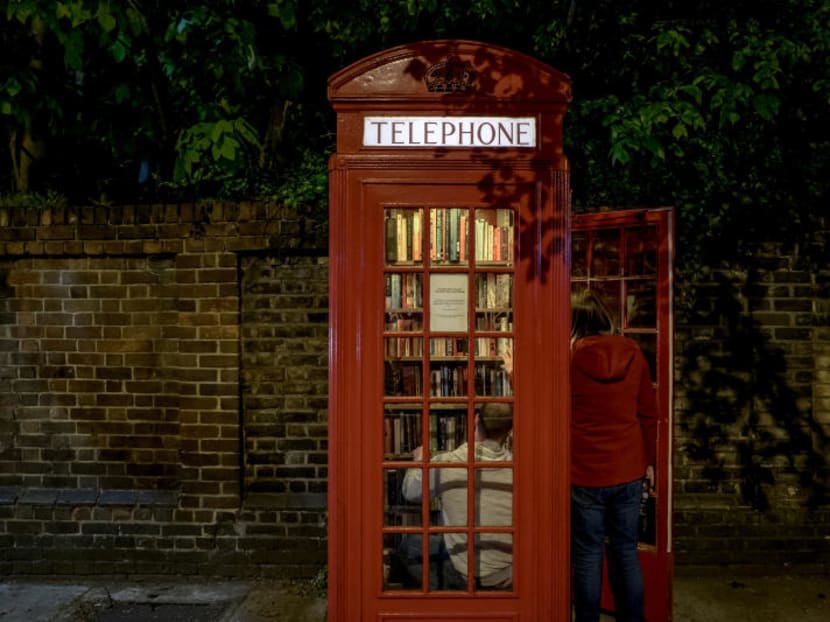 A restored phone box houses a community library in Lewisham, South London, May 3, 2018. Some of the iconic red phone booths remain as relics of the past, but many have been restored and repurposed.
