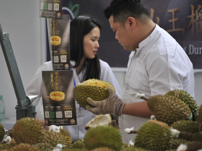 Promoters work at a booth of Musang King durians at the Malaysia Durian Festival in Nanning