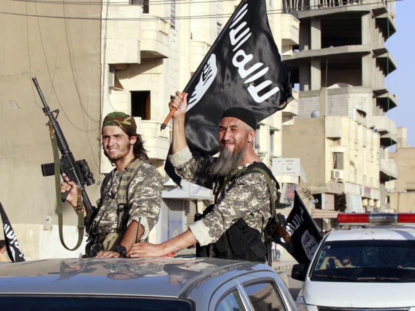 Militant Islamist fighters wave flags as they take part in a military parade along the streets of Syria's northern Raqqa province, June 30, 2014. Photo: Reuters