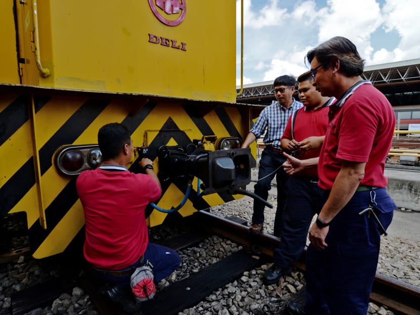 Mr Abdul Rashid Ahmad (third from right), 53, Branch Manager at SMRT examining a train with technicians. Photo: Robin Choo