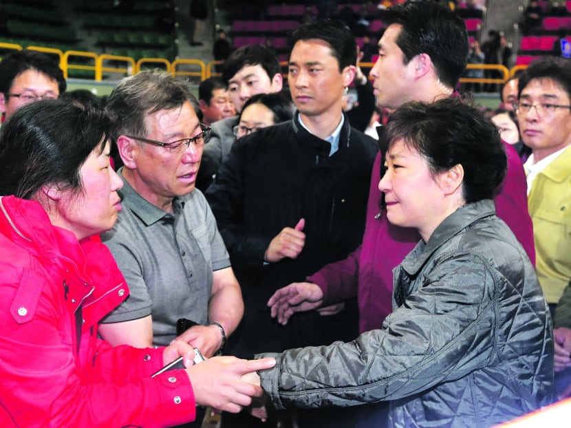 South Korean President Park Geun-hye (right) meeting family members of a missing passenger yesterday at a gym where relatives gathered. Photo: Reuters