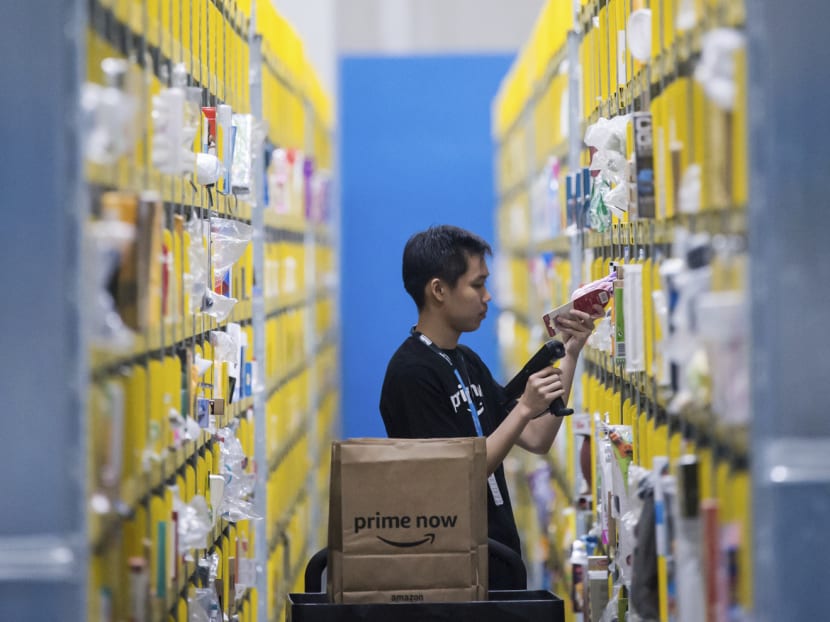 An employee scanning a product at the newly opened Amazon Prime Now facility in Singapore. Local online grocers will soon feel the heat of going toe to toe with Amazon’s one-hour and two-hour delivery guarantees. PHOTO: AP