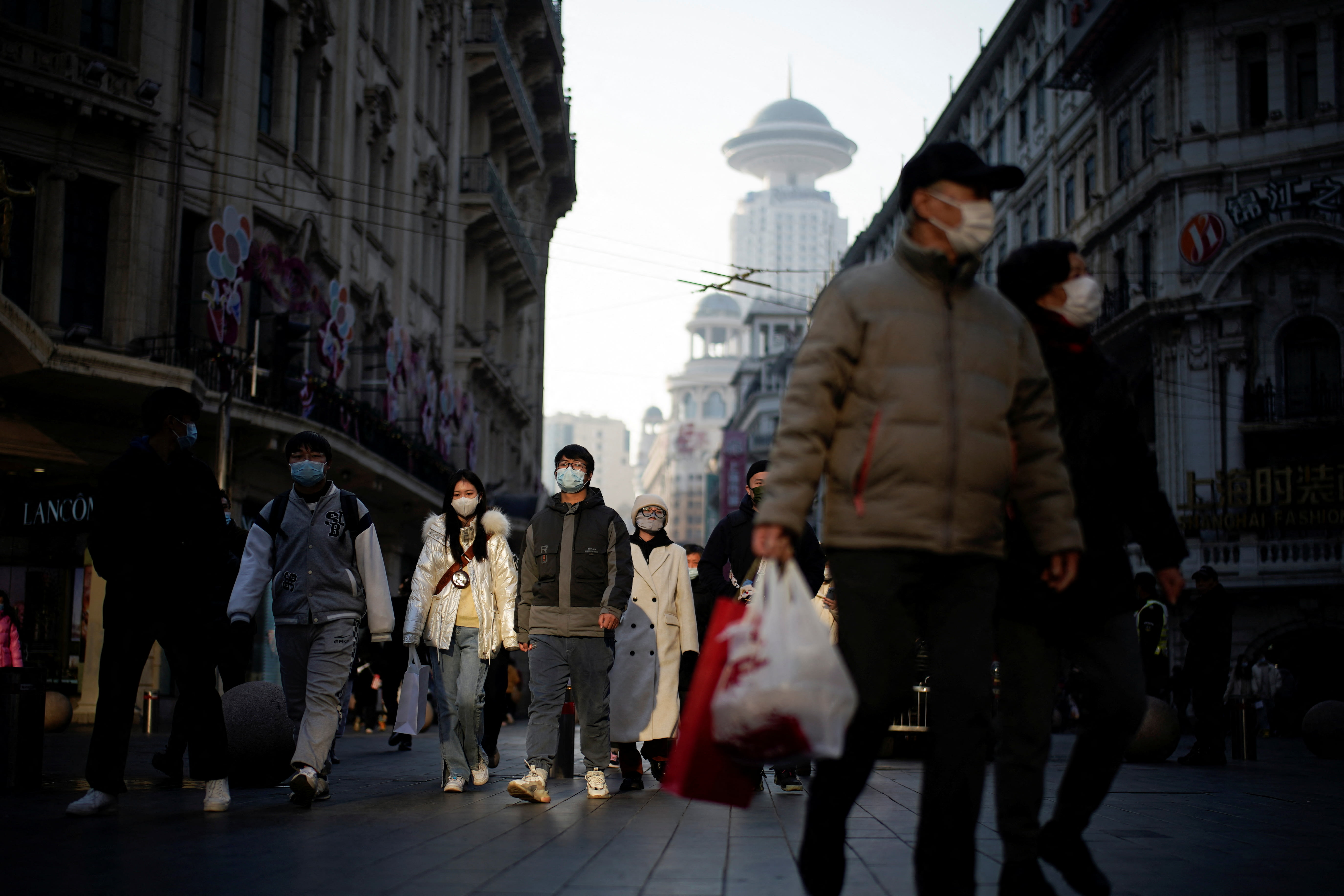 People wearing protective face masks walk on a street, following new cases of the coronavirus disease, in Shanghai, China on Dec 30, 2021. 