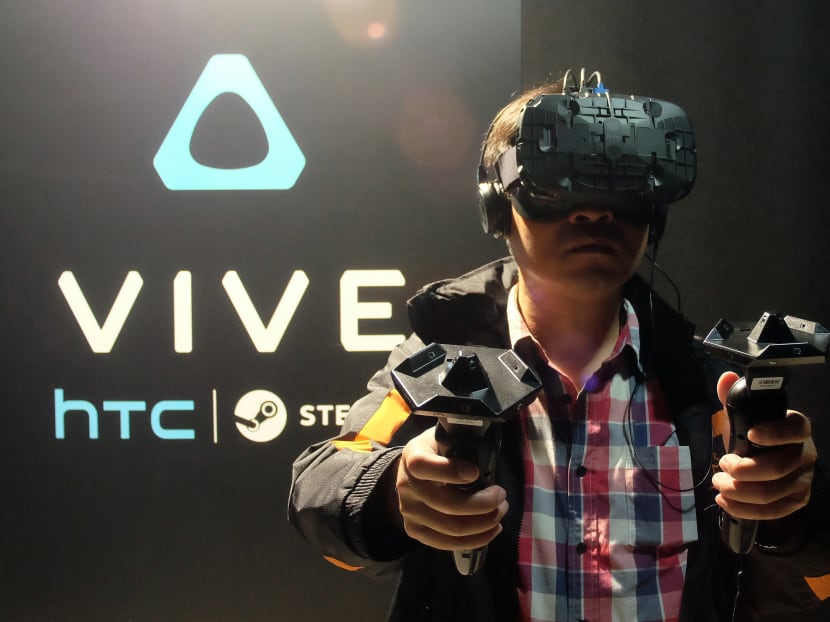 A fan wears a HTC Vive headset and holds two sensors during a promotional event held by HTC in Taipei on Dec 15, 2015. Photo: AFP