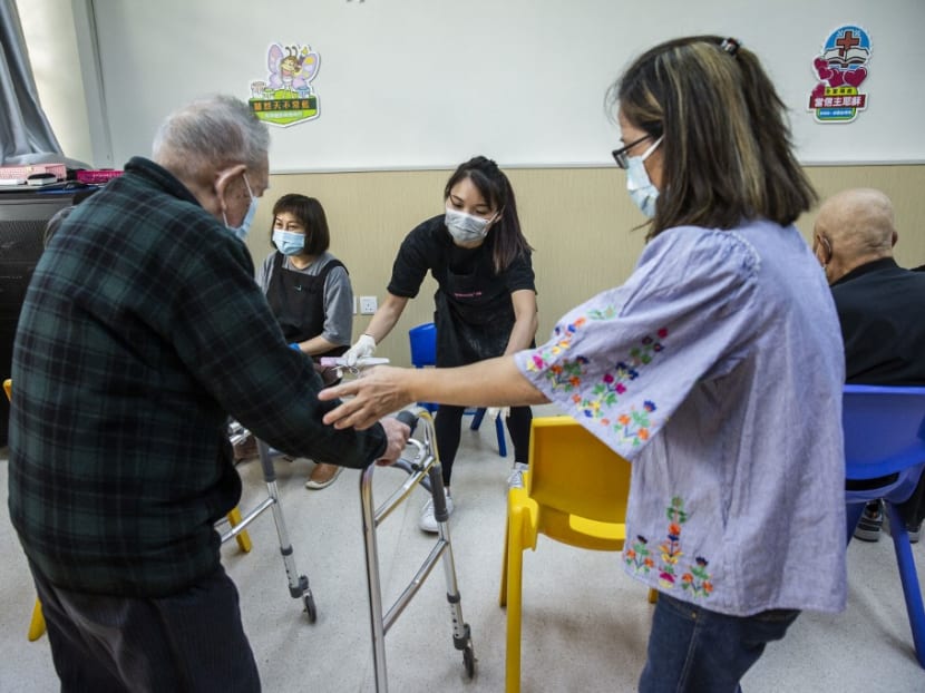 This photo taken on Nov 8, 2021 shows nail salon owner Cass Ng (centre) helping an elderly man before giving him a pedicure at a community centre for the elderly in Hong Kong as part of a charity initiative.