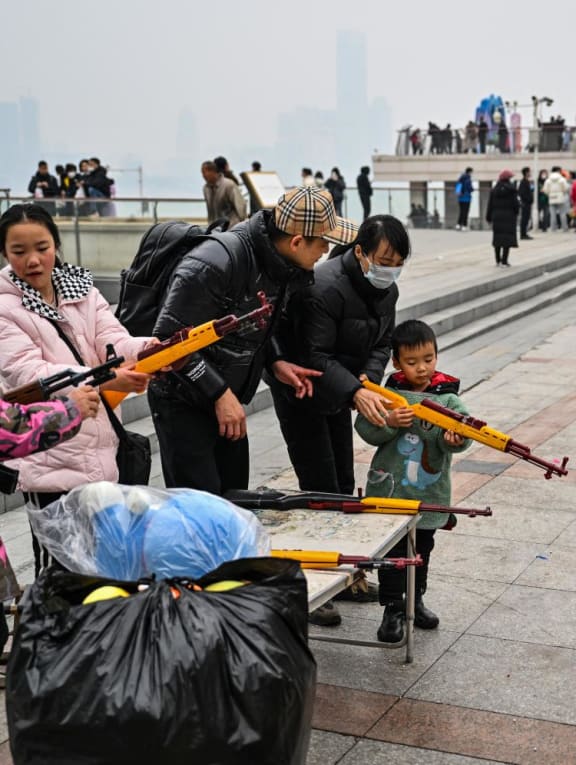 People aim to burst balloons with toy guns at a stall along the Yangtze River in Wuhan, in China's central Hubei province, on Jan 22, 2023. 
