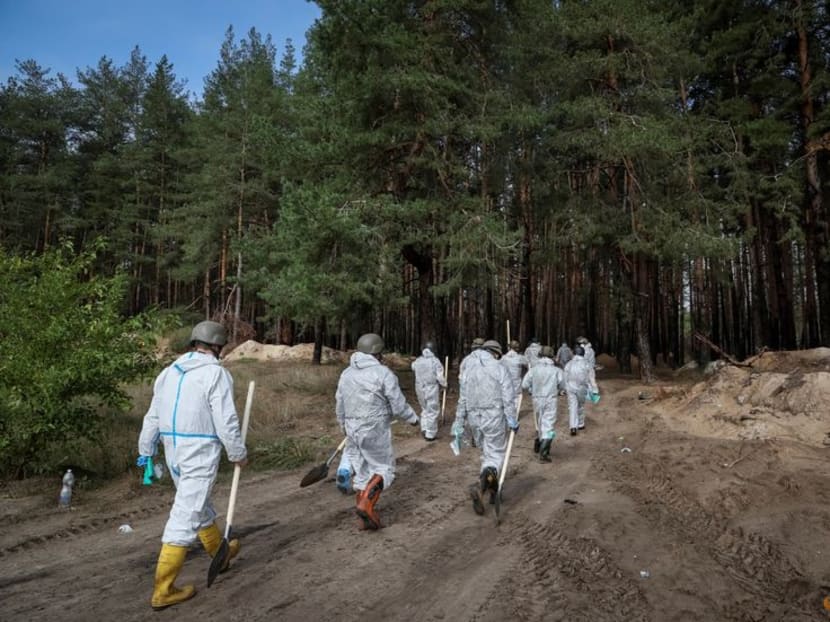 FILE PHOTO: Members of Ukrainian Emergency Service walk to work at a mass burial site during an exhumation, as Russia's attack on Ukraine continues, in the town of Izium, recently liberated by Ukrainian Armed Forces, in Kharkiv region, Ukraine September 17, 2022. REUTERS/Gleb Garanich FILE PHOTO: Members of Ukrainian Emergency Service walk to work at a mass burial site during an exhumation, as Russia's attack on Ukraine continues, in the town of Izium, recently liberated by Ukrainian Armed Forces, in Kharkiv region, Ukraine September 17, 2022. REUTERS/Gleb Garanich