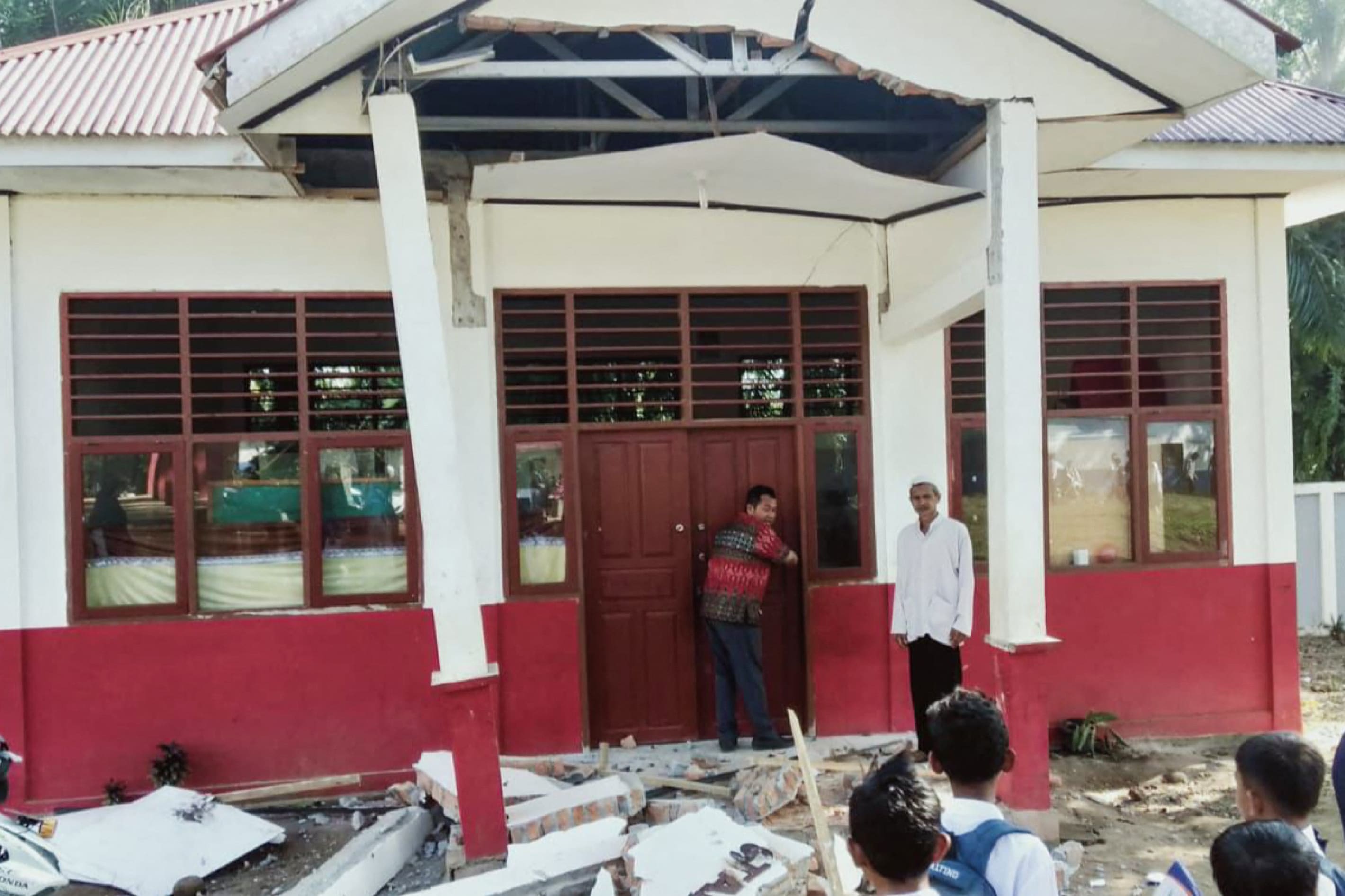Residents inspect a building damaged by a magnitude 6.2 earthquake at Kajai village in West Pasaman on Feb 25, 2022.
