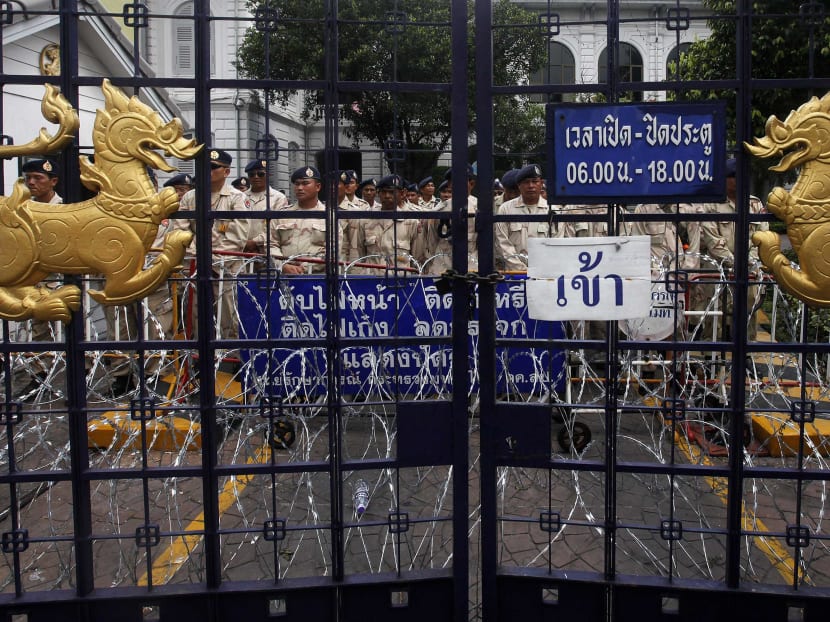 Security personnel standing behind the gates of Thailand’s Interior Ministry as protestors surrounded the various ministries yesterday. Photo: Reuters