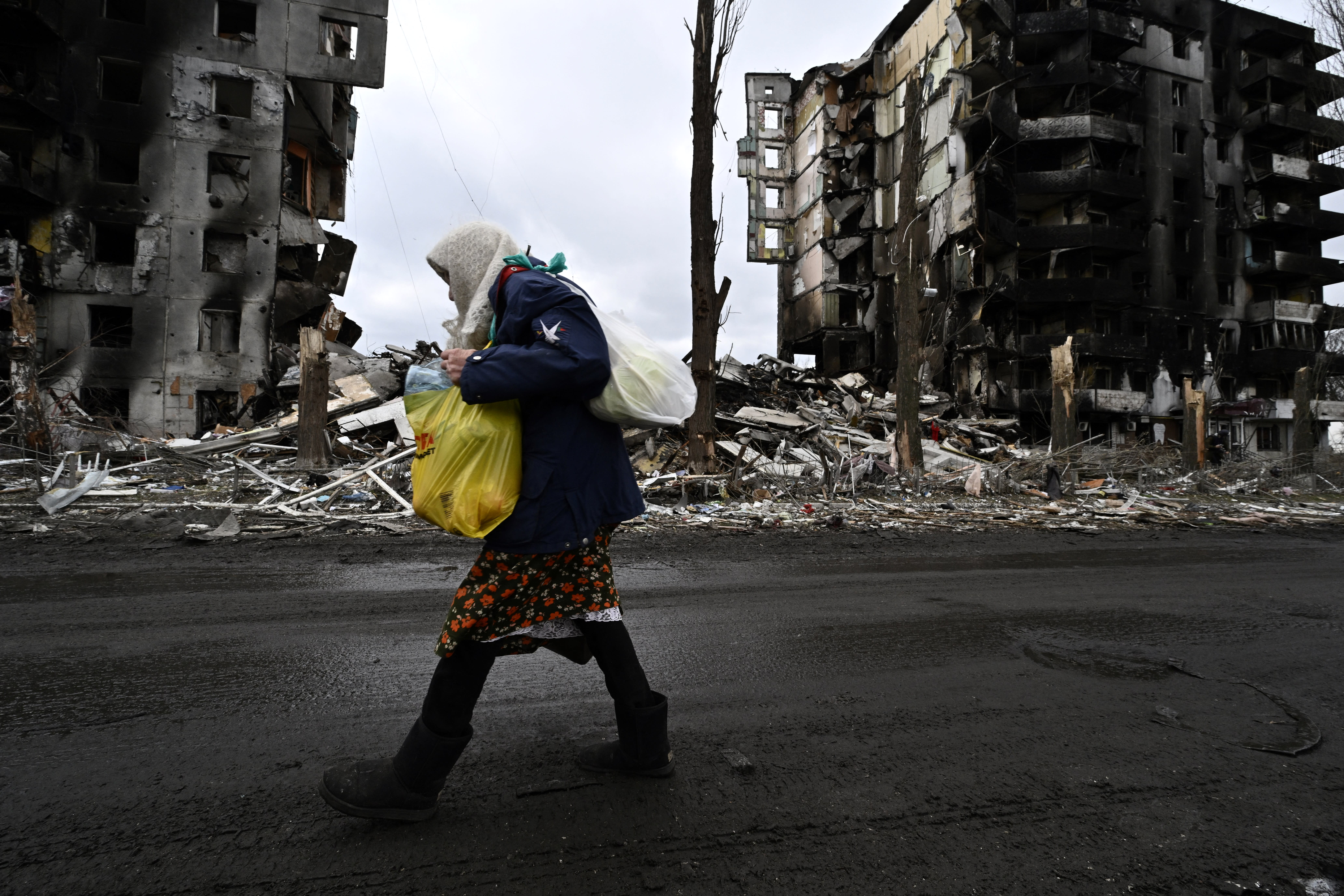 A woman walks in front of destroyed buildings in the town of Borodianka on April 6, 2022, where the Russian retreat last week has left clues of the battle waged to keep a grip on the town.