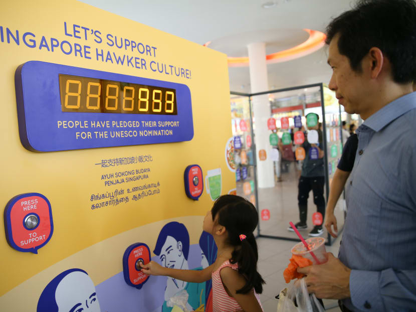 Patrons at a food centre engaging with an interactive board for the Our SG Hawker Culture travelling exhibition in 2018.