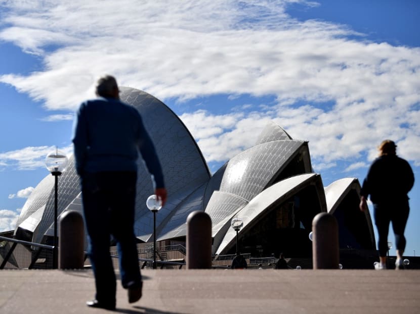 This picture taken on June 26, 2021 shows people walking in front of the Opera House, usually packed with visitors, as a lockdown in Australia's largest city Sydney was tightened on July 9, 2021.