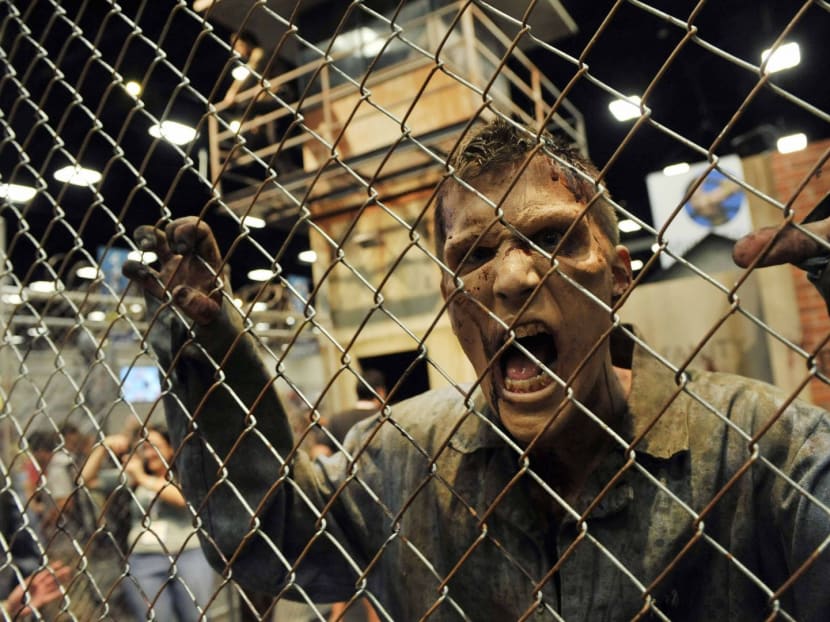 A zombie character in an exhibit inspired by the television series "The Walking Dead" screams at onlookers during the Preview Night event on Day 1 of the 2013 Comic-Con International Convention on Wednesday, July 17, 2013 in San Diego. Photo: AP