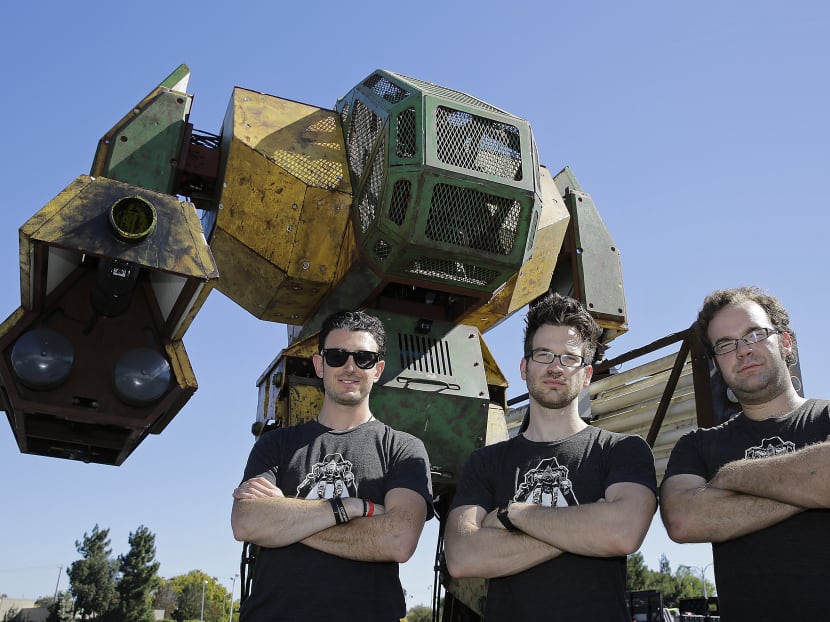 In this photo taken on Oct 9, 2015, MegaBots founders from left, Brinkley Warren, Matt Oehrlein and Gui Cavalcanti stand below their 15-foot tall, piloted Mk.II robot at the Pioneer Summit in Redwood City, Calif.  Photo: AP
